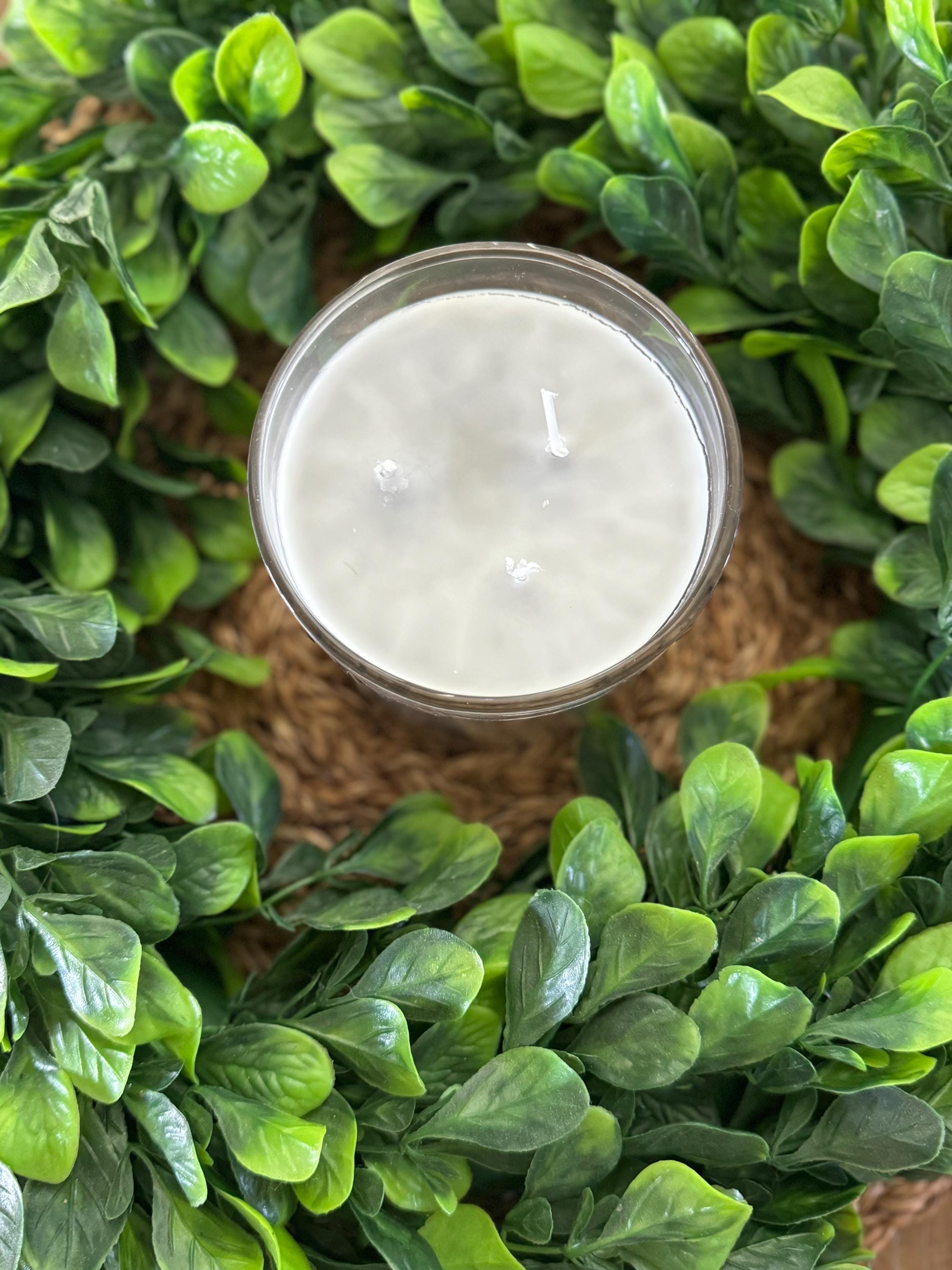 a candle surrounded by green leaves